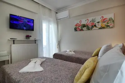 a room with two beds and a tv on the wall at Favola Golden Beach Villa in Daratso