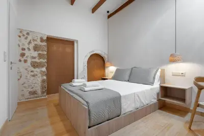 a bedroom with a large bed and a chair at Leo Apartment 2 bdr apt overlooking the harbor in Chania Town