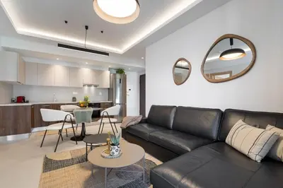 a living room with a black leather couch and a kitchen at Comfy Apt terrace and parking 800m to old town and beach in Chania Town