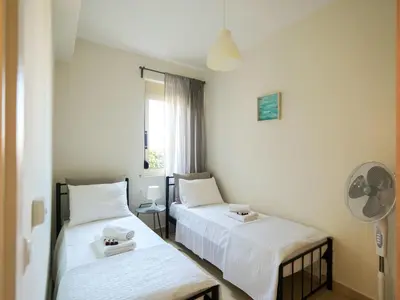 a room with two beds and a fan at Cisterna Apartment - Shared Pool in Stérnai