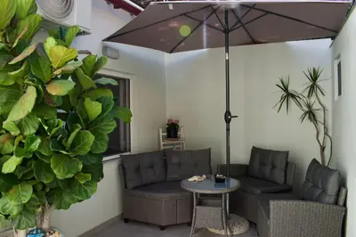 a patio with two couches and a table and an umbrella at Astrinos Apartment Simple cozy comfortable close to the beach in Chania Town