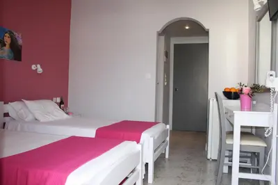 a bedroom with two beds and a table and a desk at Nereides Hotel in Kolymvari