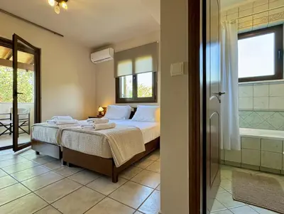 a bedroom with a bed and a bathroom with a shower at Villa Metapothia Gavalochori Crete in Gavalochori