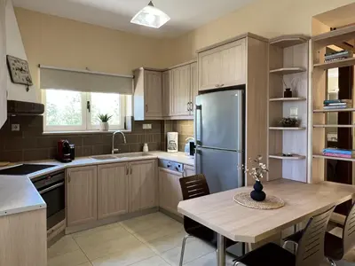 a kitchen with a table and a stainless steel refrigerator at Villa Avra Vrisses Crete in Alikampos