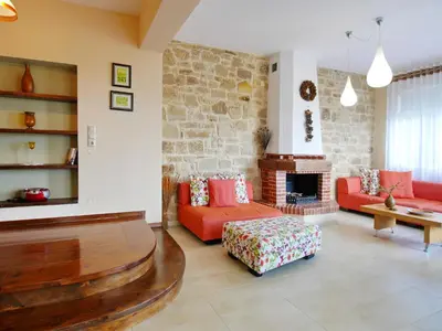 a living room with red couches and a stone wall at Villa Avra Vrisses Crete in Alikampos
