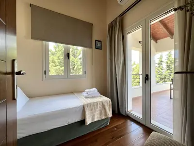 a bedroom with a bed and a sliding glass door at Villa Avra Vrisses Crete in Alikampos