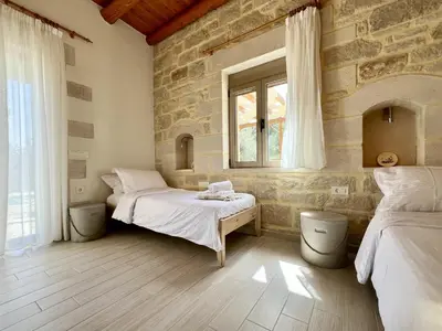 a bedroom with two beds and a stone wall at Villa Olivia with Pool Vrises Crete in Alikampos
