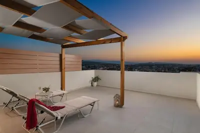 a balcony with a bench and chairs on a roof at Afrodite-Μεζονέτα στην πόλη Χανιά in Chania Town