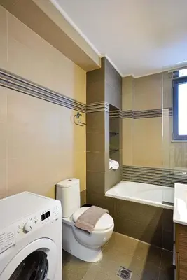 a bathroom with a washing machine and a toilet at Ionia Cozy Home in Chania Town