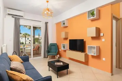 a living room with a blue couch and a tv at Orange Seaside Apartment in Galatás
