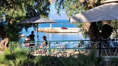 a group of people sitting at a table by the water at Sea View Modern 2BR Top Floor on Nea Chora Beach in Chania Town