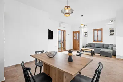 a living room with a wooden table and chairs at 2 bd sea view sun terrace apartment 500 meters walk to the beach in Galatás