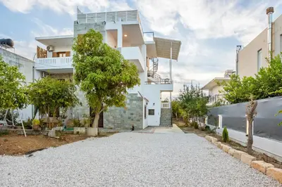 a white house with a tree in front of it at 2 bd sea view sun terrace apartment 500 meters walk to the beach in Galatás