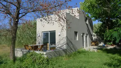 a white house with two chairs and a tree at Proimos Apartments in Gerani Chanion