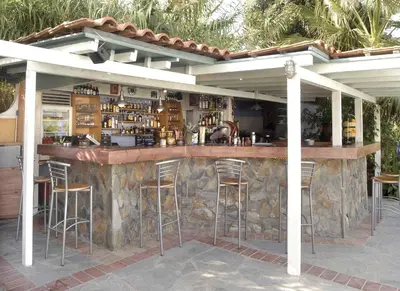 an outdoor bar with stools in front of a stone wall at Proimos Apartments in Gerani Chanion