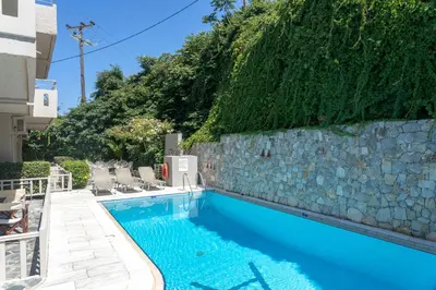 a swimming pool with a stone wall next to a building at Hotel Agapi Apartments in Plataniás
