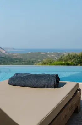 a pillow on a bed next to a pool at Villa Elia Provarma - Your villa in Chania Town