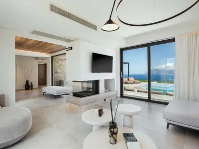 a living room with a fireplace and a tv at Rastoni Villa I ''Free'' heated pool & panoramic view in Kalivianí