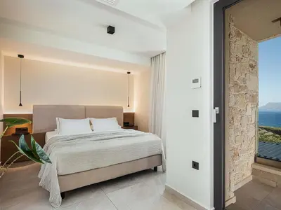 a bedroom with a bed and a large window at Rastoni Villa I ''Free'' heated pool & panoramic view in Kalivianí