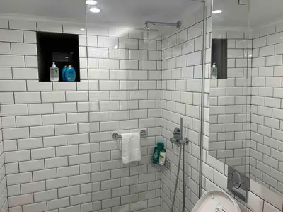 a white tiled bathroom with a shower and a toilet at Perfect home away from home in Palio Gerani