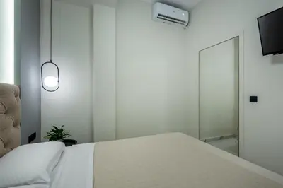 a white bedroom with a bed and a tv at Hypnos Luxury Lodgings in Chania Town