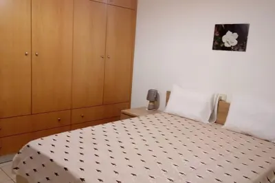 a bedroom with a bed and a wooden cabinet at COSY NEW APARTMENT- 5' to the beach, 15' to center in Chania Town