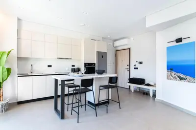 a kitchen with white cabinets and a island with bar stools at A3stays a cozy vacation retreat in Chania Town