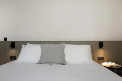 a large white bed with white pillows and a white headboard at A3stays a cozy vacation retreat in Chania Town