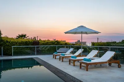 a swimming pool with lounge chairs and an umbrella at Villa Shell in Tersanas