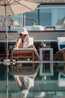 a woman sitting on a bench next to a swimming pool at Villa Shell in Tersanas