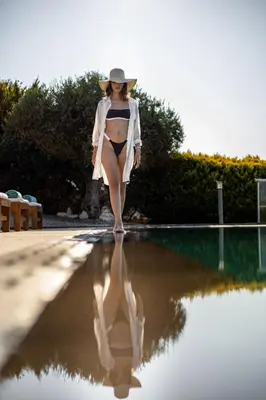 a woman in a bikini walking next to a swimming pool at Villa Shell in Tersanas