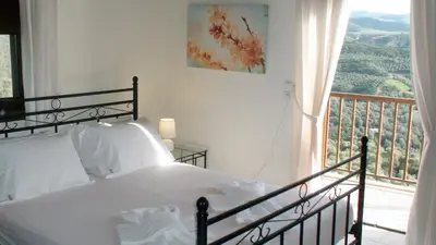 a bedroom with a white bed and a balcony at Aori Hillside Villa in Kántanos
