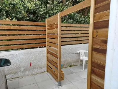 a wooden privacy fence with a chair on a patio at Kristy's House with garden in Chania Town