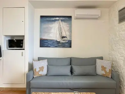 a living room with a couch and a painting of a sailboat at Waves - Seaside Escape in Chania Town