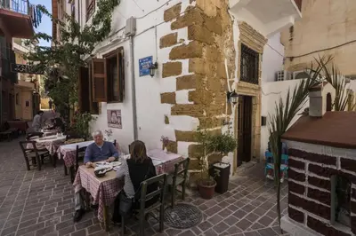 two people sitting at tables outside a building at Eulogia Casa in Chania Town