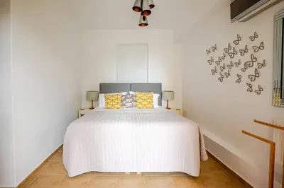 a white bedroom with a white bed with yellow pillows at Villa Anthos - Superb panoramic sea and hill views with private pool in Gavalochori