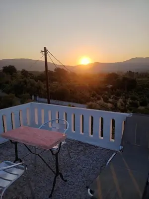a table and chairs on a balcony with the sunset at Stefanos Garden in Arménoi