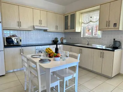 a kitchen with a white table with fruit on it at Aegean View Villa, 2-min Drive to Almyrida Beach in Almirida
