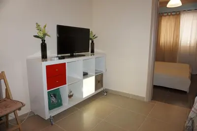 a living room with a tv on a white cabinet at Seaside Cottage in Kato Daratso