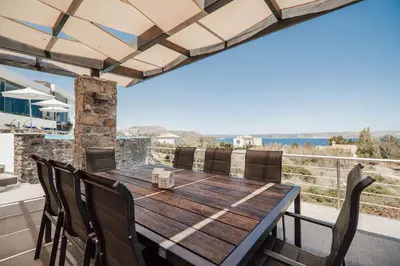 a wooden table and chairs on the balcony of a house at Villa Kera Panorama by PosarelliVillas in Vamos