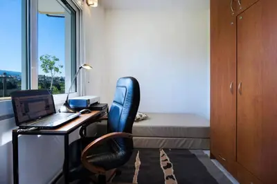 a room with a desk with a laptop and a bed at Penthhouse next to the beach in Souda