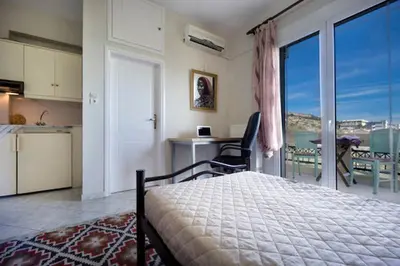 a bedroom with a bed and a kitchen with a balcony at Penthhouse Studio next to the beach in Souda