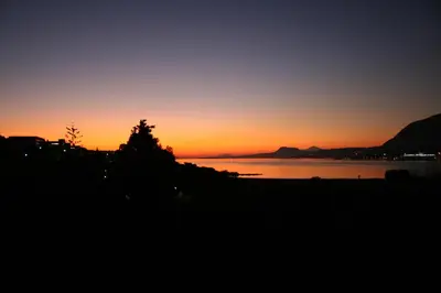a sunset over the water with a tree in the foreground at Penthhouse Studio next to the beach in Souda
