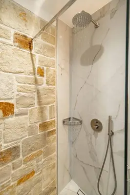 a shower with a glass door and a stone wall at Fantasea Villas, villa Lux in Galangádhos