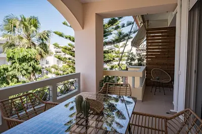 a balcony with a table and chairs and palm trees at Tessera Alfa city apartment in Chania Town