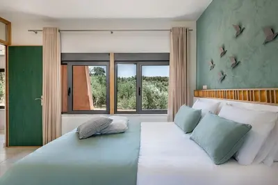 a bedroom with a large bed with blue and white pillows at Villa AnnaNiko, Luxury Villa, 2 Heated Pools, Jacuzzi, Gym, Stunning Views, Green Energy in Gerani Chanion