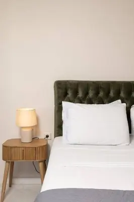 a bed with a green headboard and a table with a lamp at The White Marble Luxury City Apt in Chania Town