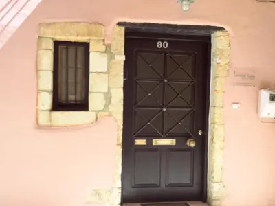 a black door on the side of a pink building at Venetian House in Chania Town