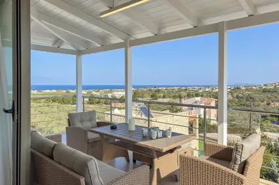 a patio with a table and chairs on a balcony at Olive Chrysi Luxury Villa with in-room plunge pool in Chania Town