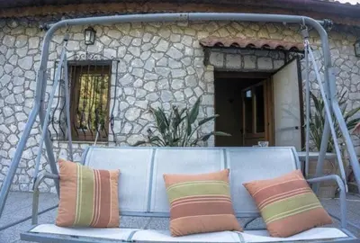 a bench with three pillows on it in front of a building at Diving into silence - Traditional Stone House in Kakópetros